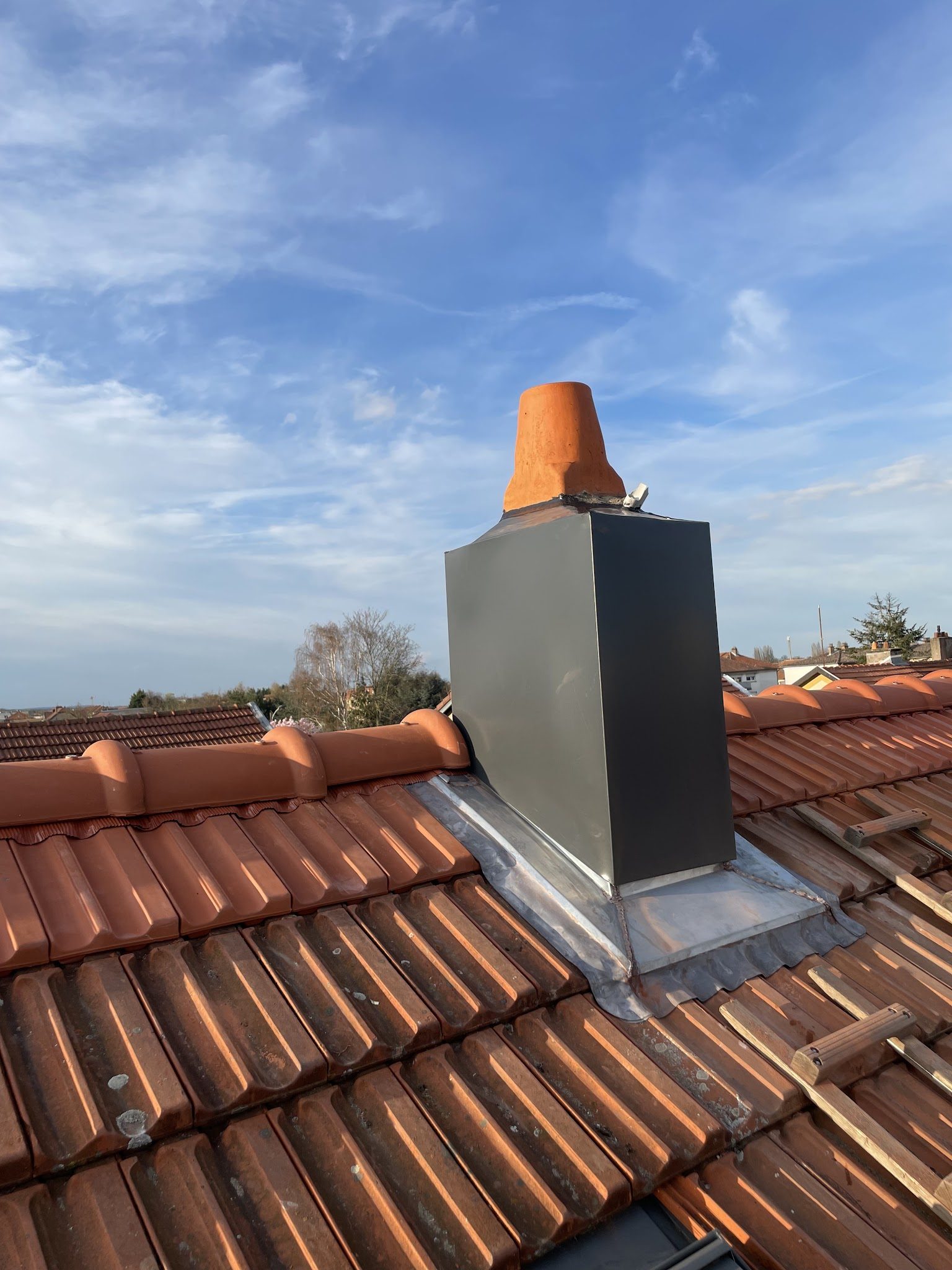 Habillage de cheminée en zinc sur un toit de tuiles
